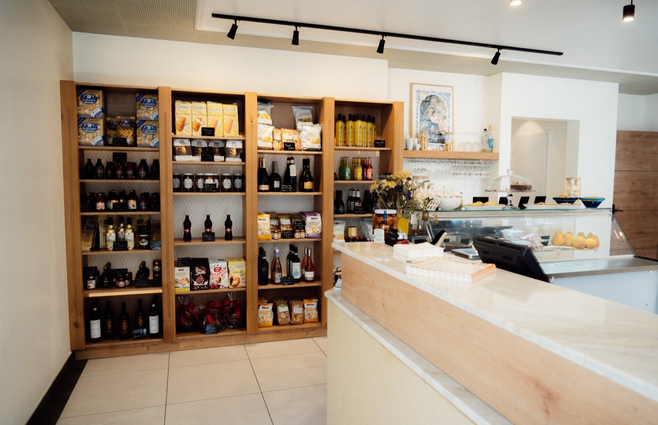 L'épicerie du restaurant : de hautes étagères en bois garnies de produits italiens, face au comptoir clair.